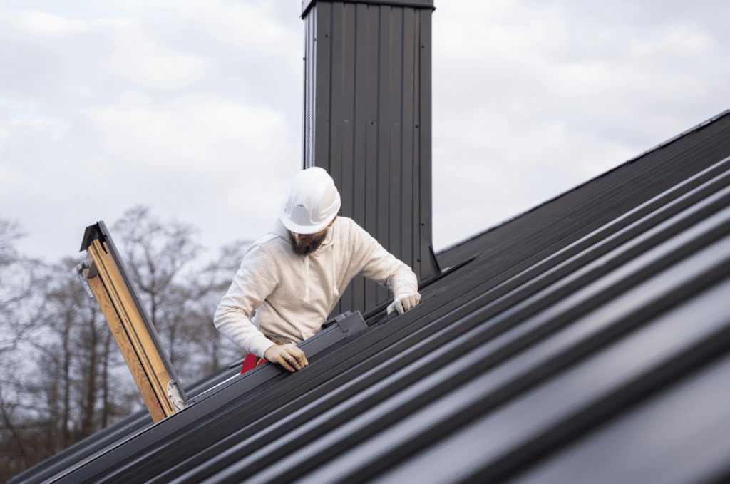 Roofer installing metal roof panels, performing professional roof repair and installation work