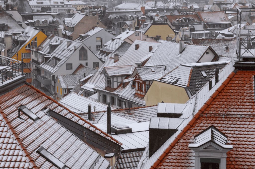 Roofer installing metal roof panels, performing professional roof repair and installation work
