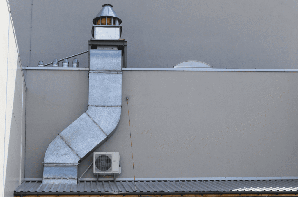 Commercial roof with metal exhaust duct and vent stack installed for safe airflow and weather protection