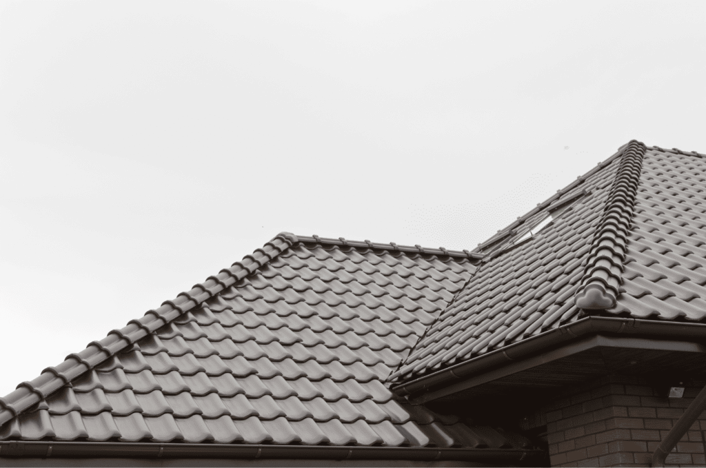Residential tile roof with visible gaps and lifted sections, repaired roof damage caused by age and weather exposure