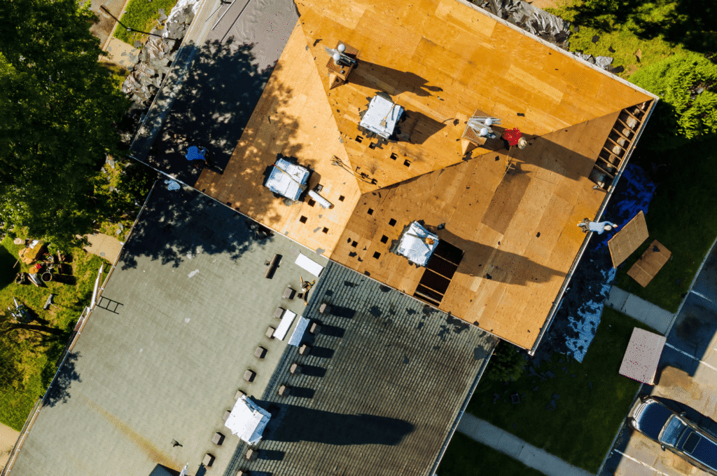 Picture showing aerial view of roofing crew replacing sections during new roof installation & final roof estimate