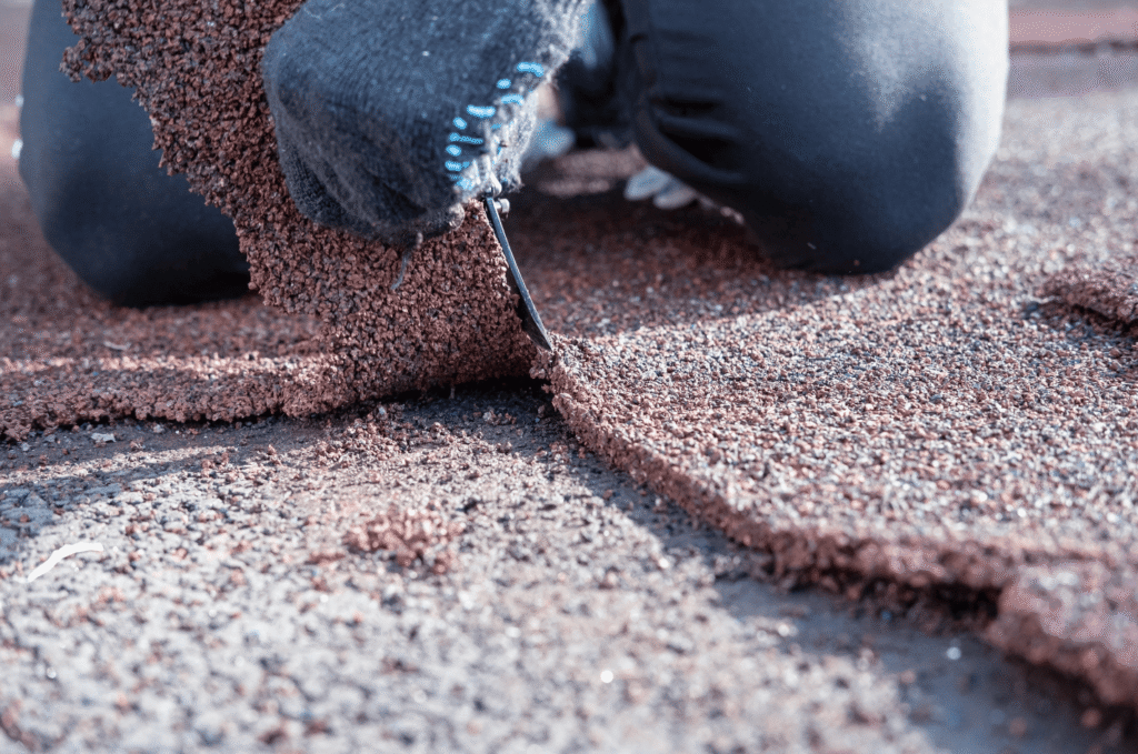 Close-up of damaged asphalt shingles showing clear shingle granule loss and exposed underlayment beneath