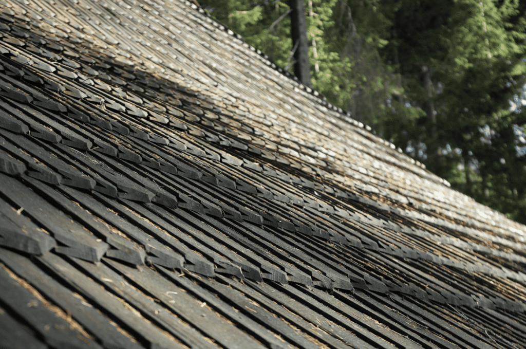Image showing bad roof installation by misaligned and lifting wood shingles across a sloped residential roof