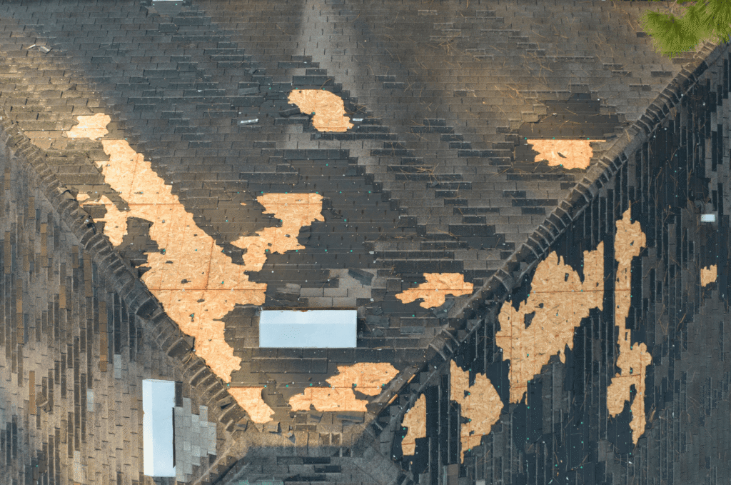 Bad asphalt shingle roof installation leading to severe shingle failure and exposed roof decking on a damaged home roof