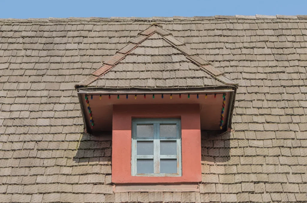 Roof sagging around dormer window with visible dip and misaligned shingles indicating structural roof damage