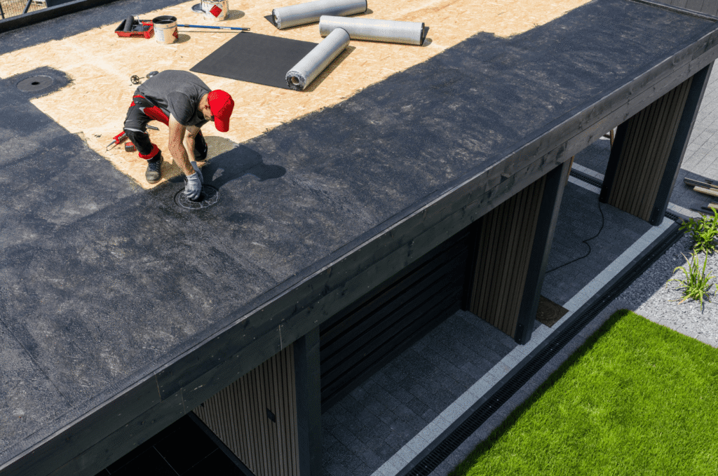 Worker installing waterproof roofing material on a flat roof during a professional roof repair project.