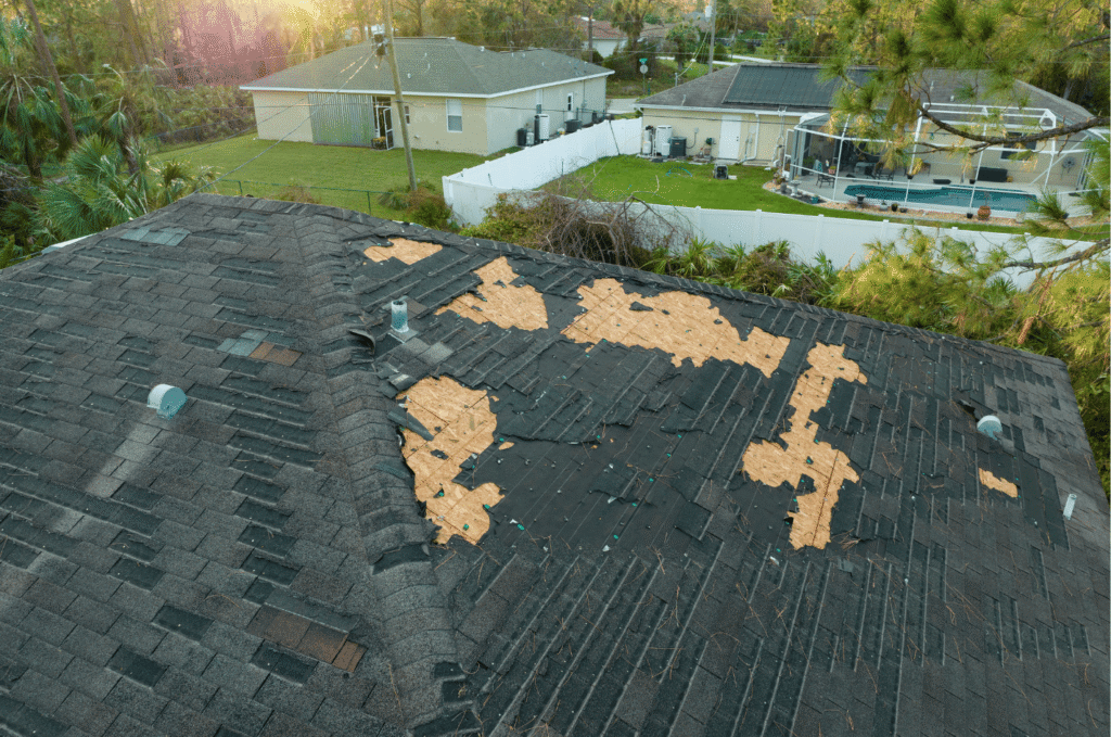 Aerial view of a house with severe roof damage where many shingles have been torn off