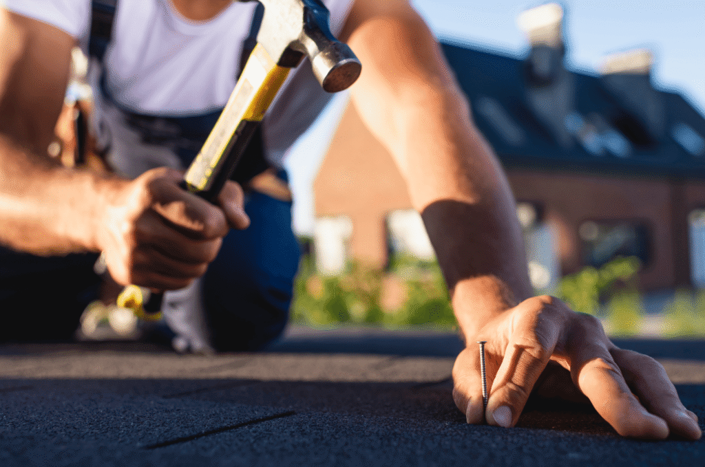 Contractor securing roofing material with a hammer during a professional roof repair.