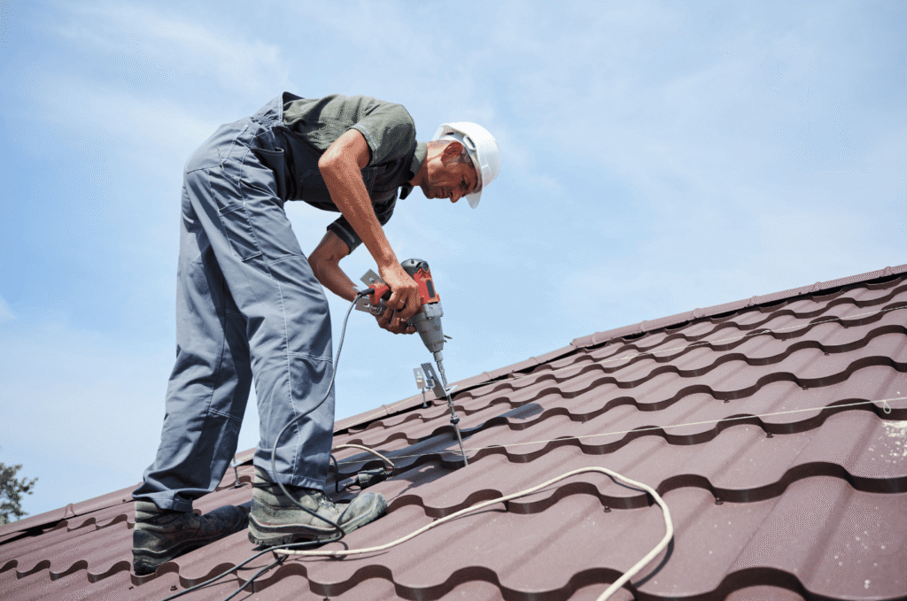 Technician using a drill on a metal roof during maintenance by experienced roof repair companies