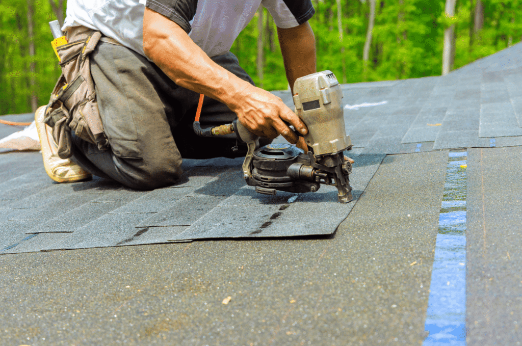 Worker installing shingles during a roof replacement using tools to secure materials and create a strong roof system