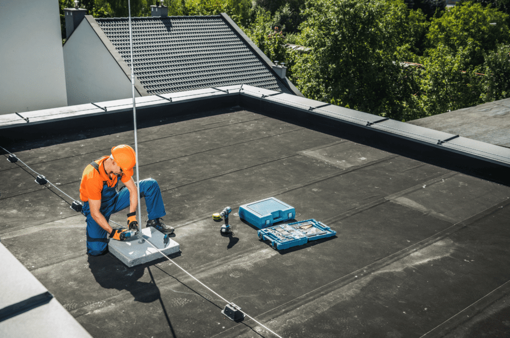 Worker installing safety anchors on an EPDM roof, preparing a flat roof surface to improve safety and long-term durability