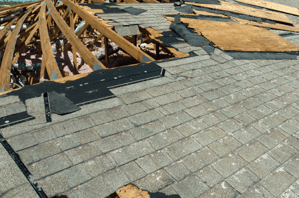 Storm-damaged asphalt roof with missing shingles and exposed decking needing emergency roof repair in Boston