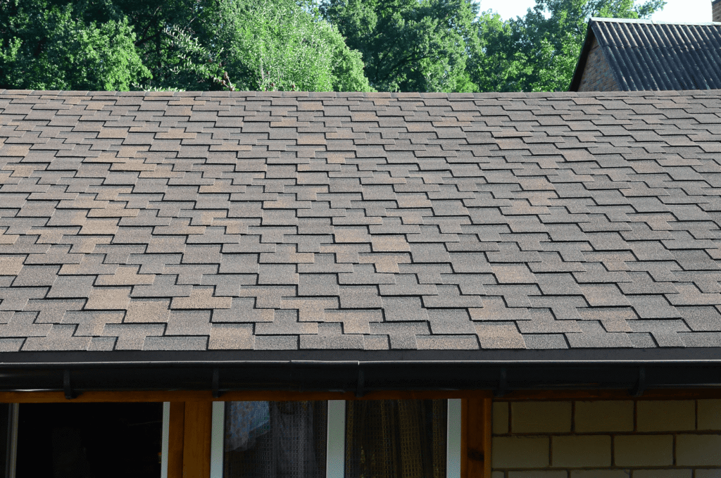 Residential asphalt shingle roof with gutters, showing signs homeowners may need a Boston roof repair contractor