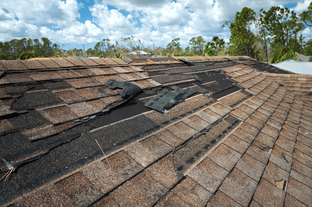 Storm-damaged residential roof showing missing and torn asphalt shingles with exposed underlayment requiring roof repair
