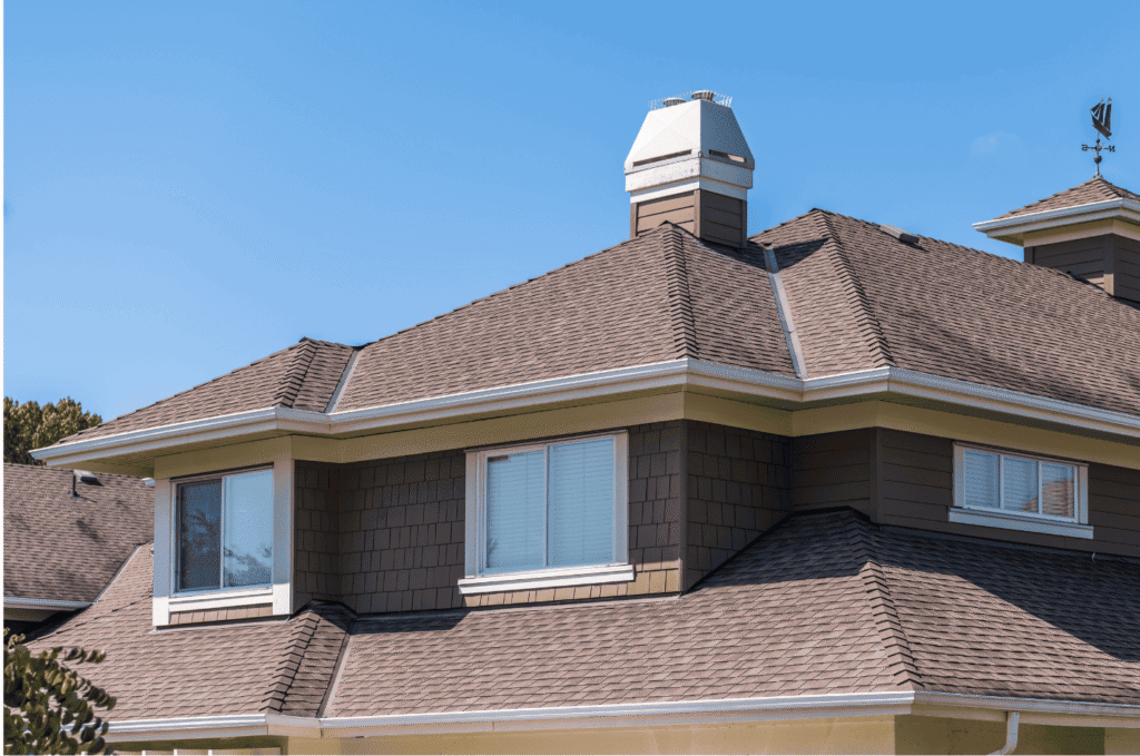 Well-maintained asphalt shingle roof with chimney and gutters after seasonal inspection to prevent leaks and roof damage