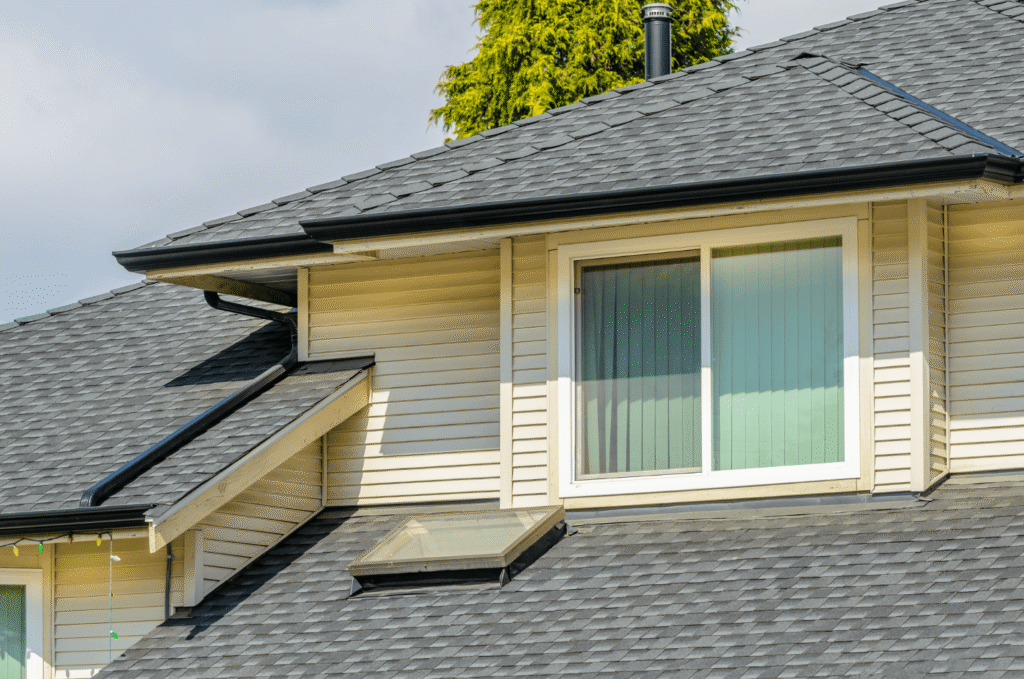 Suburban home roof with shingles, gutters, skylight, and valleys showing common roof leaking causes during heavy rain storms