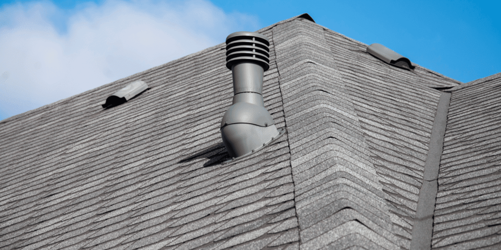 Roof vent on a gray shingle roof under blue sky, showing how poor attic ventilation can affect summer roof health over time