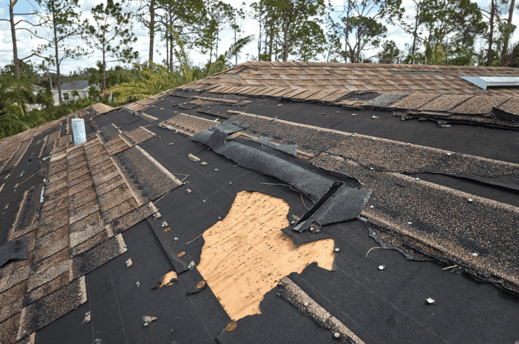 Damaged shingle roof with missing sections and exposed decking, showing how roof problems can worsen when airflow is poor