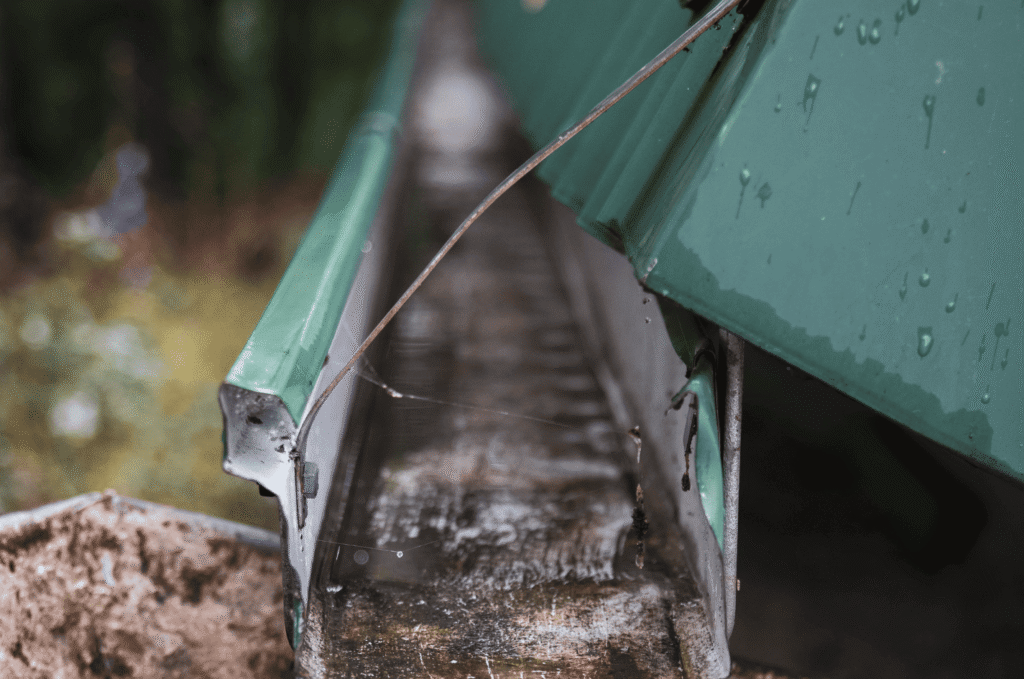 Roof drain pipe dripping water near the home, showing drainage problems that can affect foundation and structure