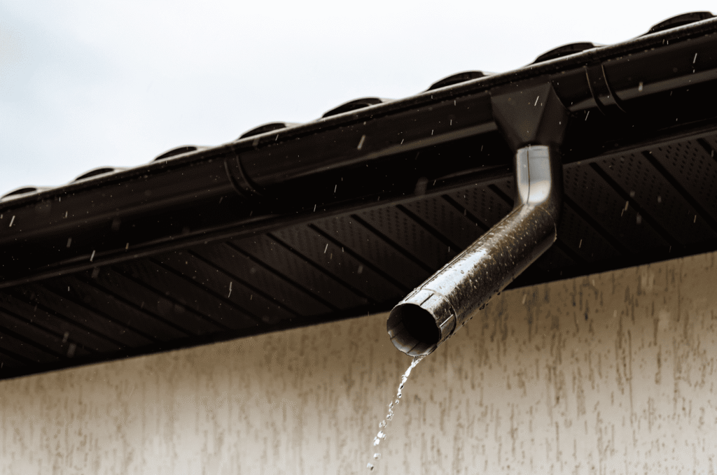 Rainwater flowing from a downspout after rain, showing how roof drainage problems can make gutter leak signs harder to trace
