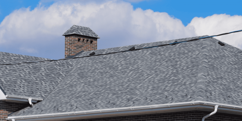 Clean asphalt shingle roof on a brick Boston home, showing where hidden attic mold may start under the roof deck area.