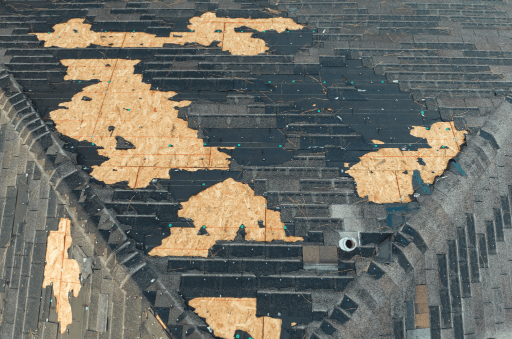 Damaged shingle roof with exposed decking showing roof leak causes near roof edges, valleys, and gutter runoff after storms 