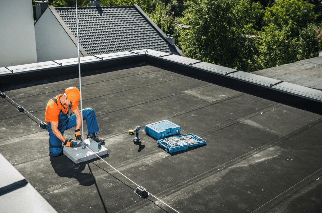 Flat roof technician checking rooftop equipment, showing how drainage layout and roof details should be inspected after rain.