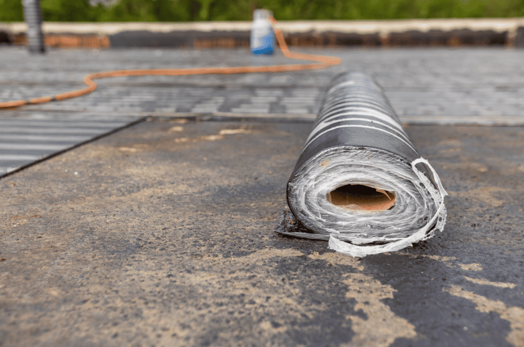 Roll of roofing membrane on a flat roof surface, showing material used for roof membrane repair and replacement options.