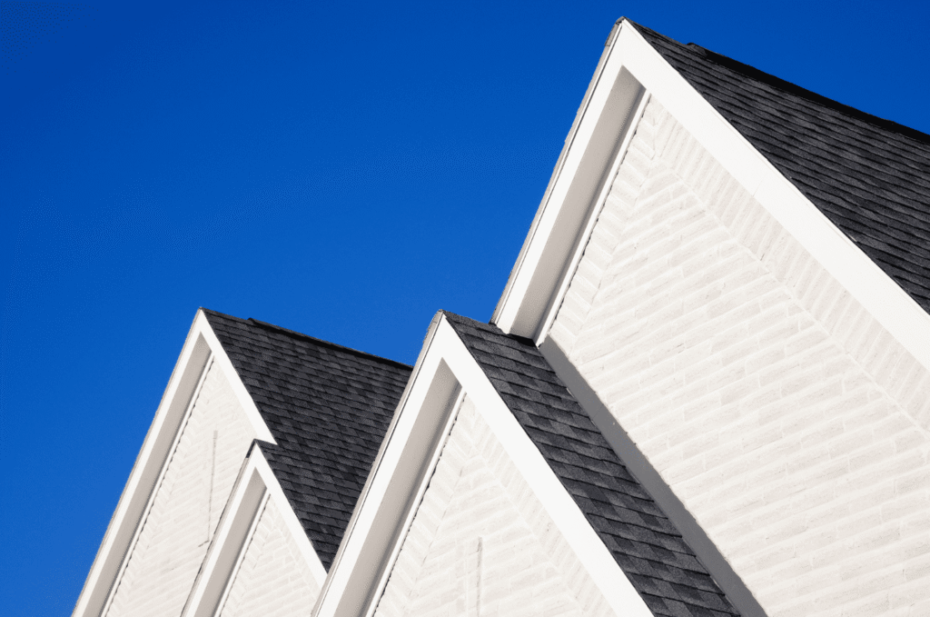 White home with multiple gable roofs and dark shingles, showing roof and soffit areas related to proper attic ventilation.