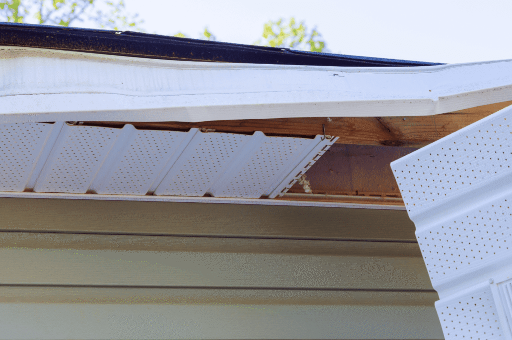 Open soffit panel showing exposed wood near the roof edge, a sign of rotted fascia and soffit water damage on a Boston home