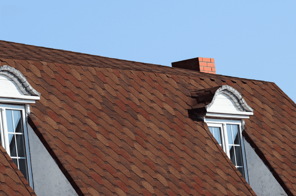 Residential shingle roof under a clear summer sky, showing key areas to include in a Boston summer roof maintenance checklist