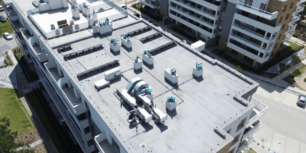 Aerial view of a flat commercial roof with HVAC units and drainage, the focus of a summer commercial roof maintenance check