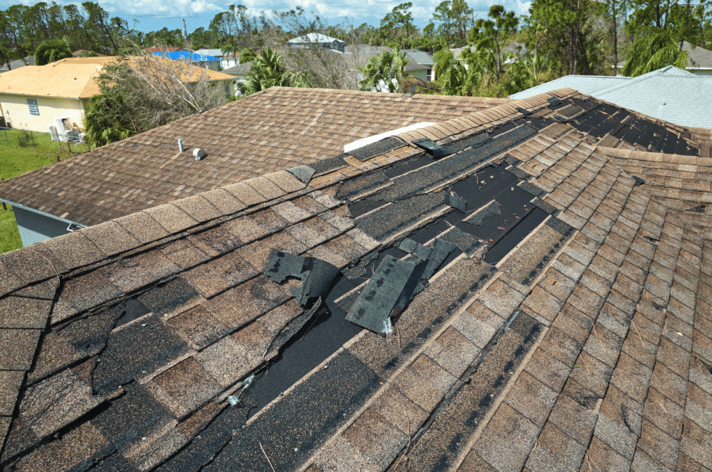 Damaged and missing asphalt shingles exposing underlayment, showing clear exterior roof warning signs on a Boston home roof