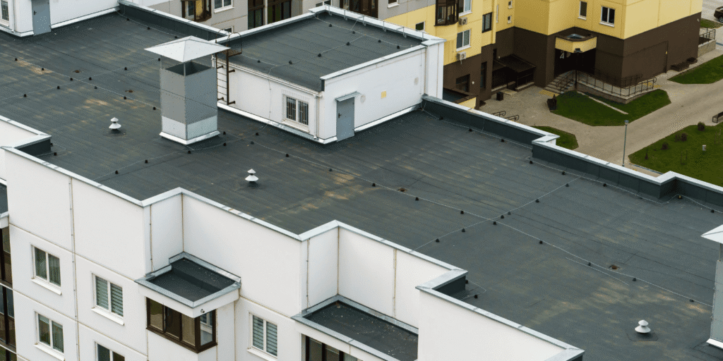 Aerial view of flat commercial roofs with membrane seams and drains, the common trouble spots behind most flat roof leaks