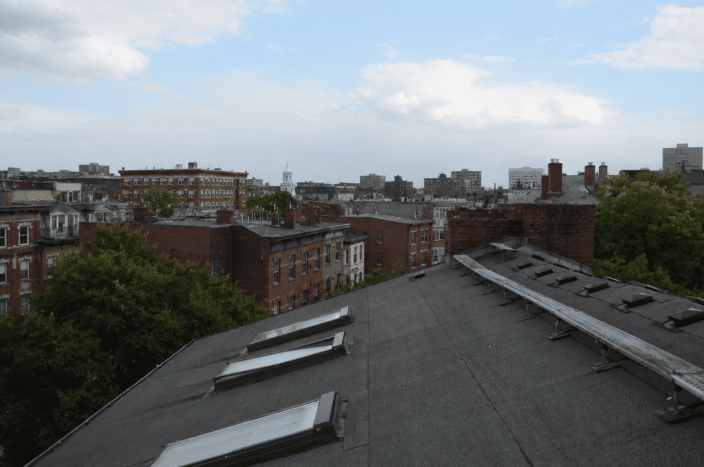 Close-up of a low-slope roof membrane with skylights and drainage details, showing how flat roofs manage water slowly.