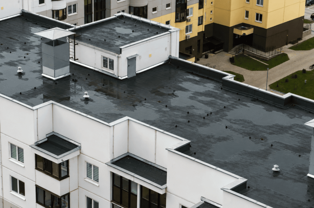 Ponding water across a flat roof membrane showing drainage issues that can increase the risk of leaks and surface damage.