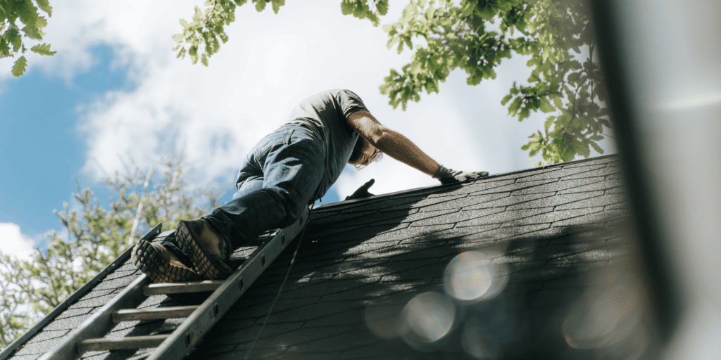 Roofer inspecting an asphalt shingle roof for early roof maintenance warning signs on a residential home in the Boston area