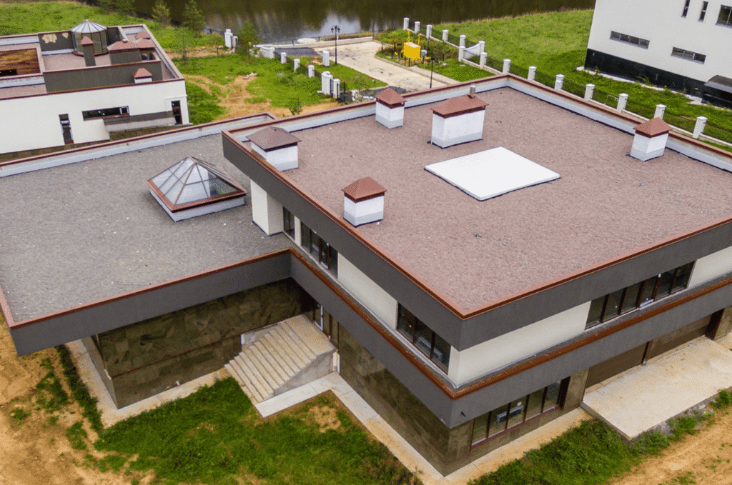 Aerial view of a building's flat roof with skylight and parapet, showing why low-slope roofs are prone to flat roof leaks