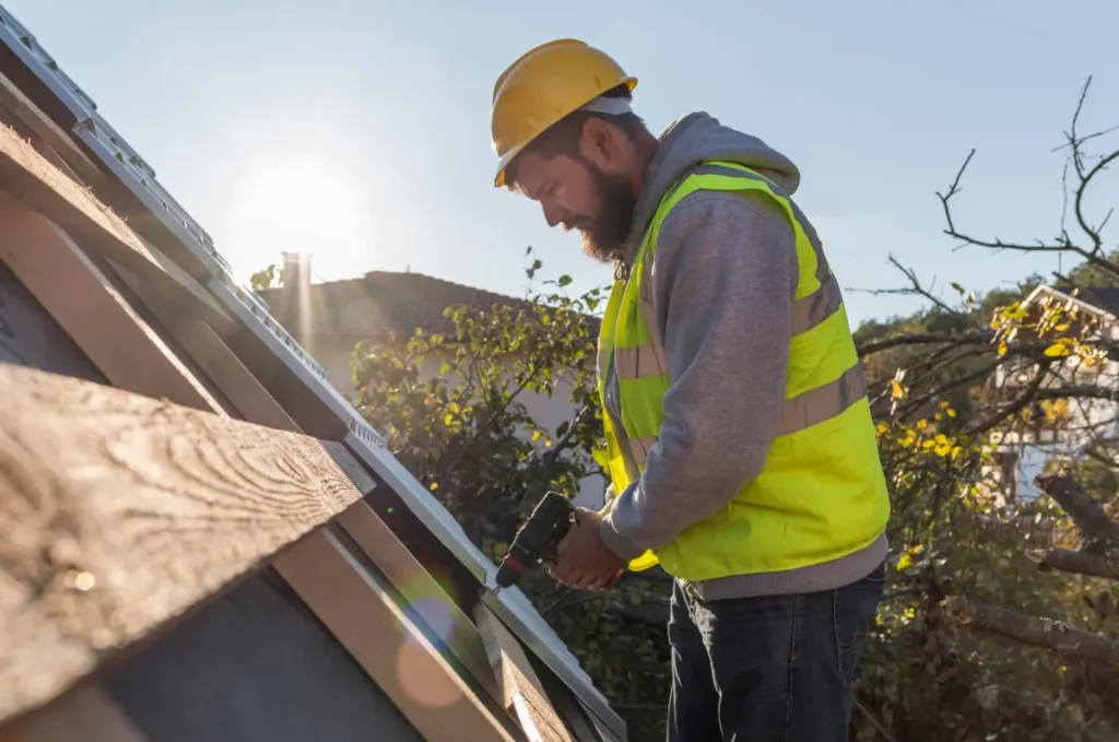 Roofer inspecting and patching a small damaged area on an asphalt shingle roof